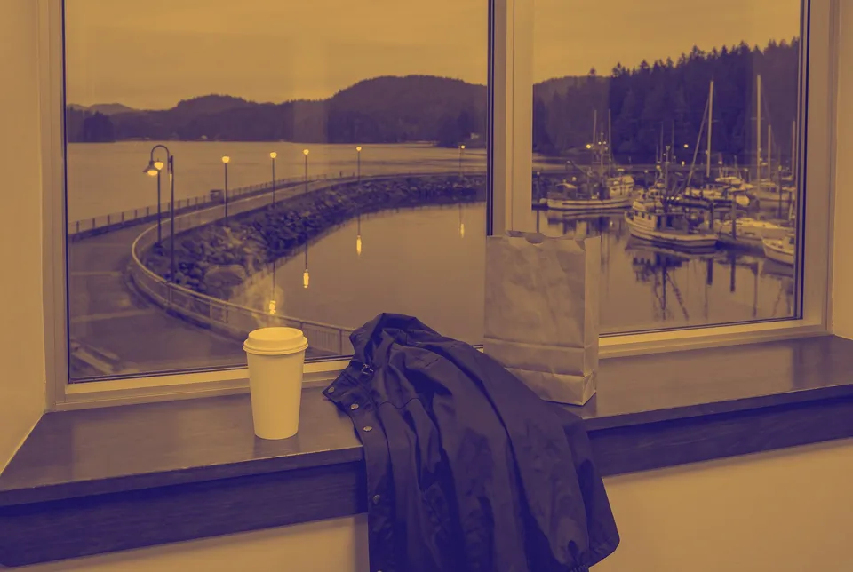 Coffee cup on a window ledge above the harbour